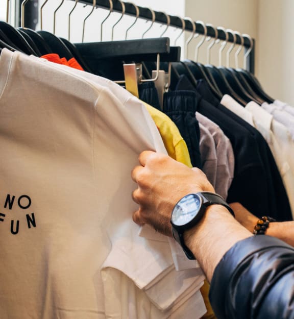 a man selecting clothes from a rack in a clothing store