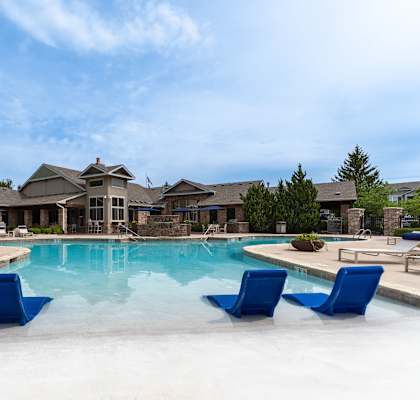 A large house with a pool and blue chairs.