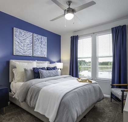 a blue and white bedroom with a bed and a ceiling fan