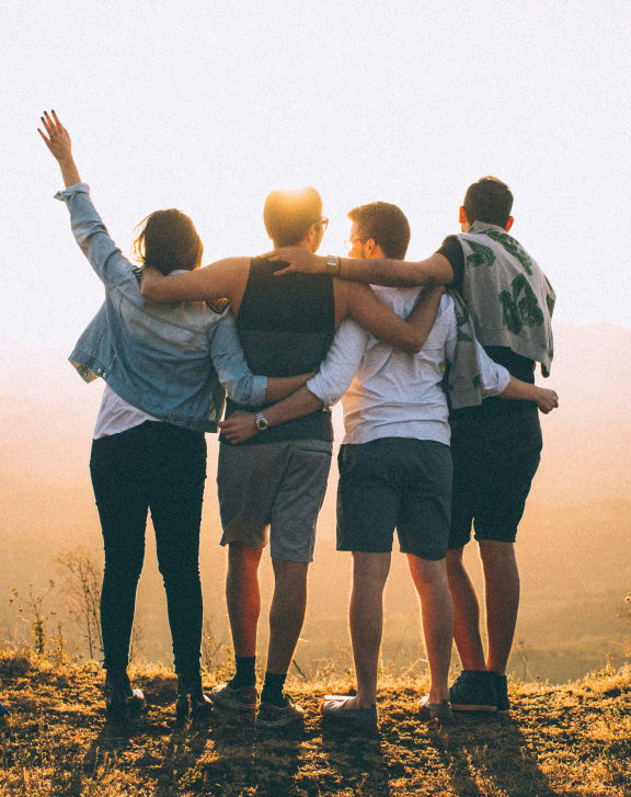 a group of people standing on a hill with their arms around each other