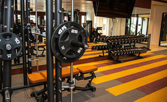 A gym with a red and yellow floor and a variety of weightlifting equipment.