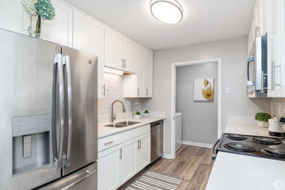 a kitchen and a dining room with a table and a refrigerator  at Laurelwood Apartment Homes, Laurel, Mississippi