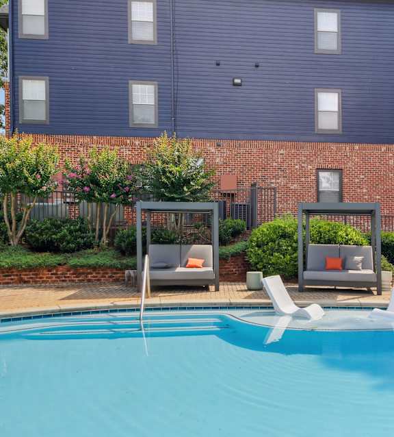 A blue swimming pool in front of a brick building.