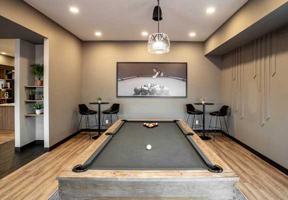 A pool table is in the middle of a room with a light hanging from the ceiling.