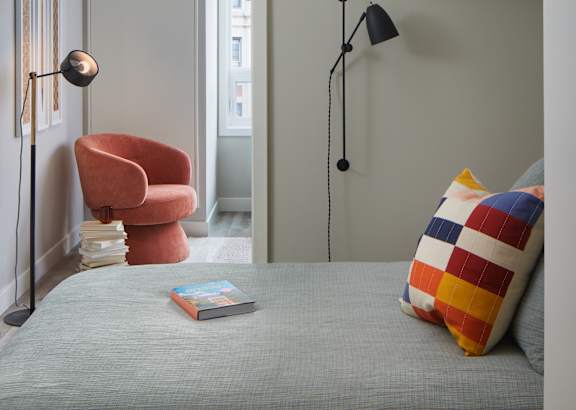 a bedroom with a bed and a chair and a reading lamp