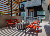 Thumbnail 8 of 8 - A patio with a striped couch and red chairs.