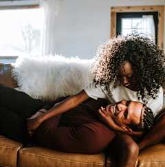A man and woman are cuddling on a brown couch.