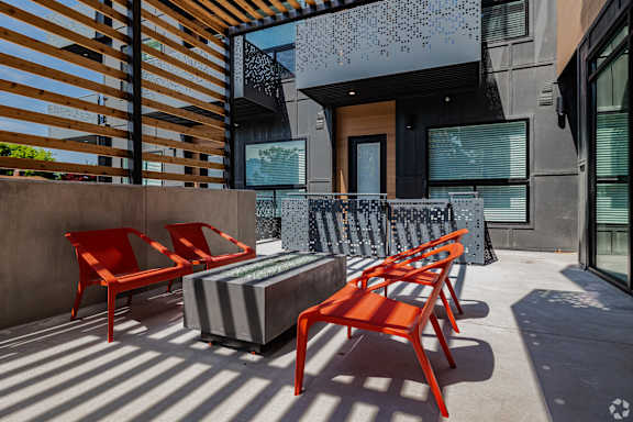 A patio with a striped couch and red chairs.