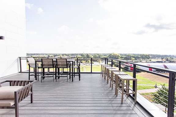 A wooden deck with chairs and a table overlooking a field.