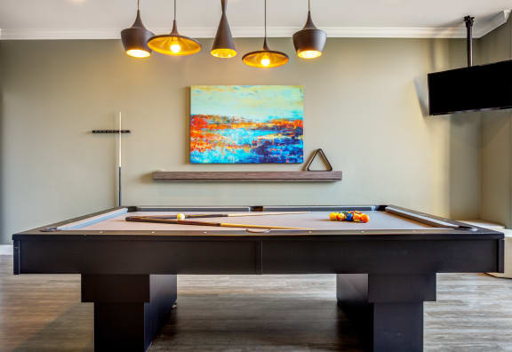 a pool table in a room with a painting on the wall