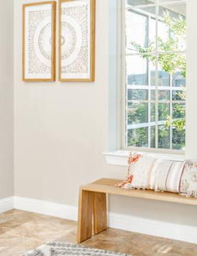 A pair of artworks hang on a wall above a bench.