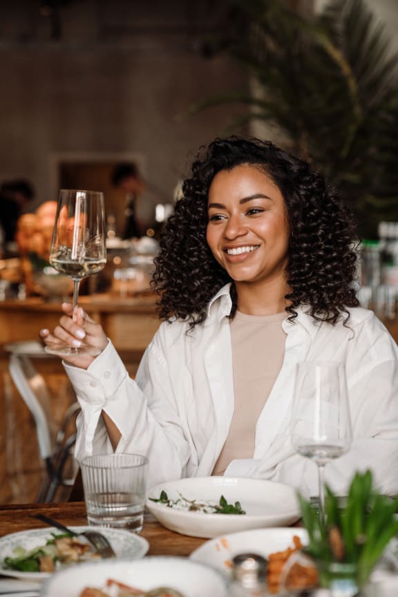 a woman sitting at a table holding a glass of wine