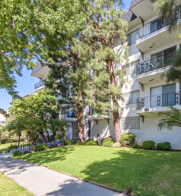 an apartment building with a lawn and trees in front of it