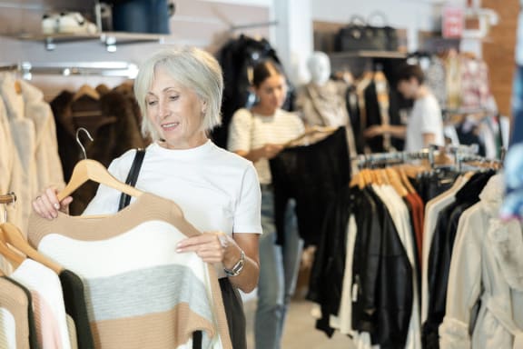 a woman holding a dress on a hanger in a clothing store