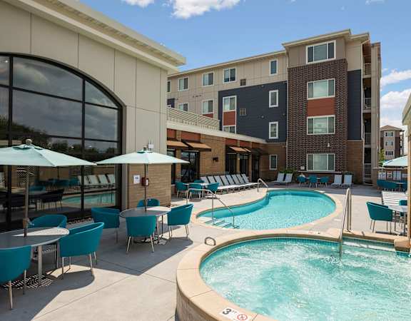 A pool area with a hot tub and chairs.