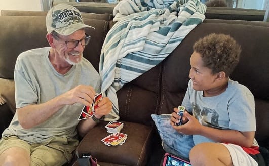 a man and a boy sitting on a couch playing cards