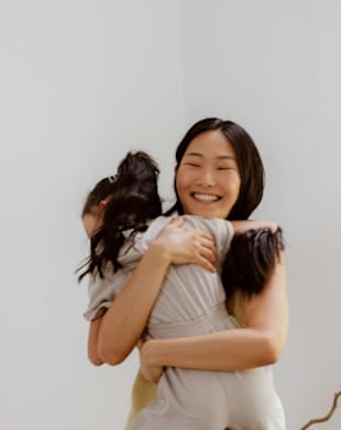 A woman is hugging a child from behind.