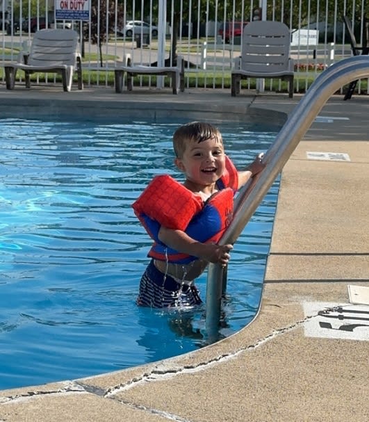 a young boy in a pool with a life jacket
