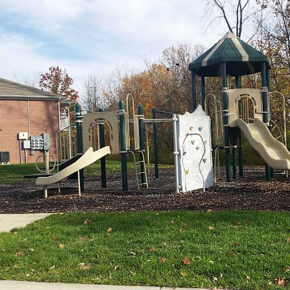 A playground with a green slide and a white slide.