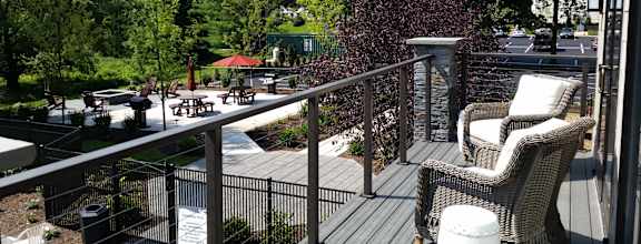 A balcony with a chair and a table overlooking a green area.