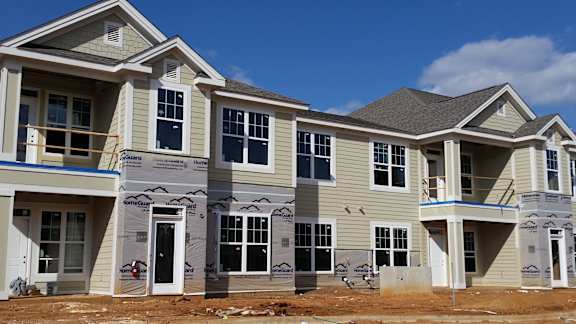 A row of houses under construction with the brand name "Crestone" on the siding.