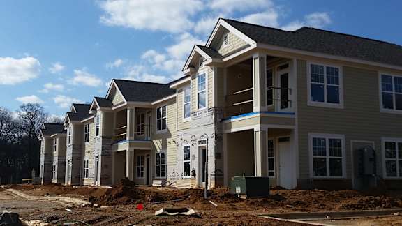 A row of houses under construction with a clear blue sky.