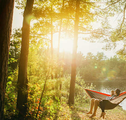 a couple relaxing in a hammock by a lake