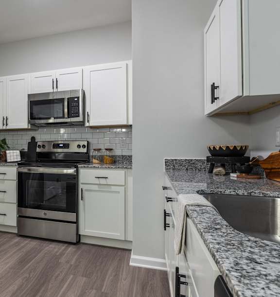 A kitchen with a refrigerator, oven, and microwave.