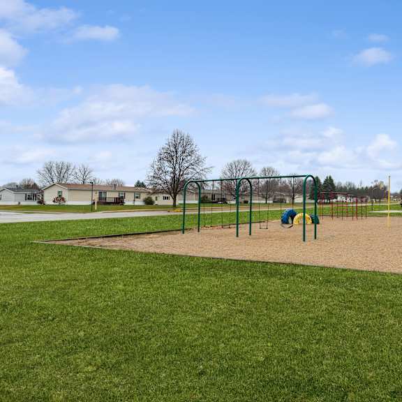 A playground with a blue umbrella and a green slide.