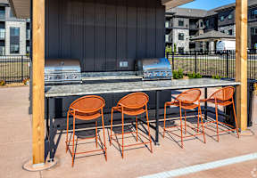 a bar with chairs in front of a grill