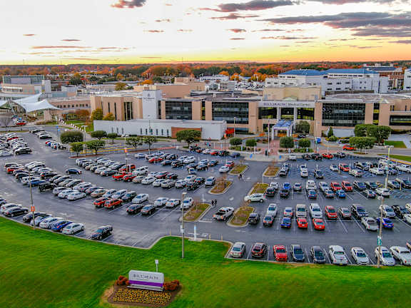 A parking lot with cars and a building in the background during sunset at Spring Lake Apartments in Greenville, NC, 27835