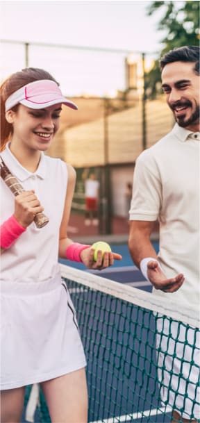 a young woman holding a tennis racket and ball next to a tennis net and young man