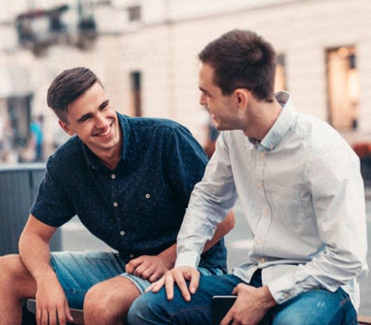 two men sitting on a bench talking to each other