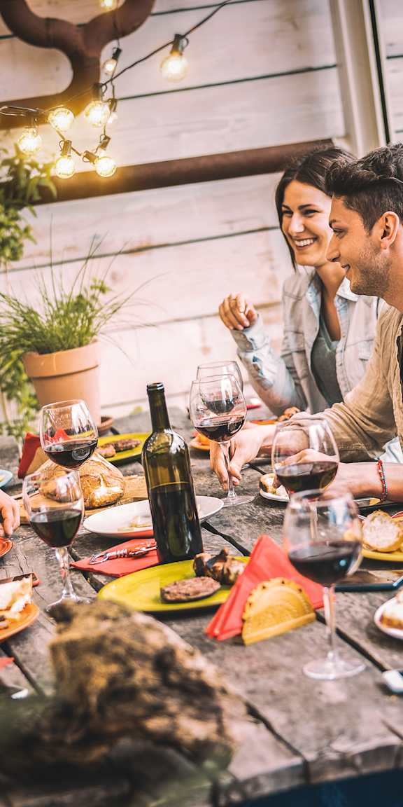 A group of people are enjoying a meal together at a wooden table.