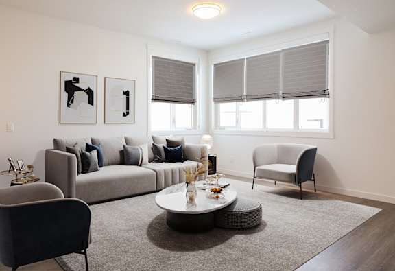 A living room with a grey couch, a grey armchair, a grey coffee table, and two framed pictures on the wall.