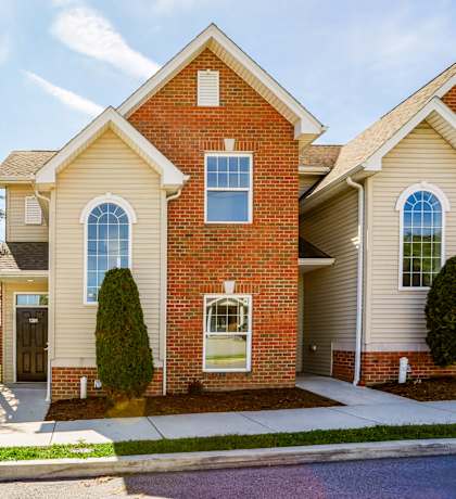 A two-story house with a brick facade and a large front yard.