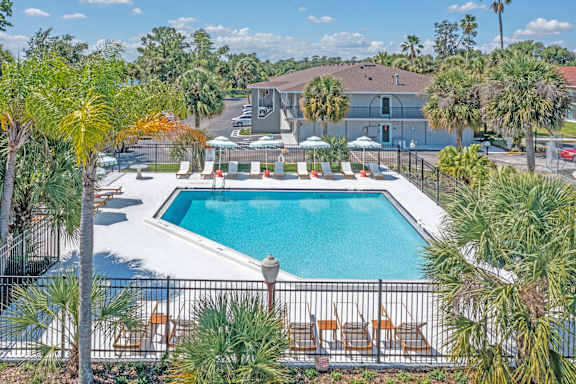 a swimming pool with chairs around it and a building in the background at The Teale, Kissimmee, FL, 34746