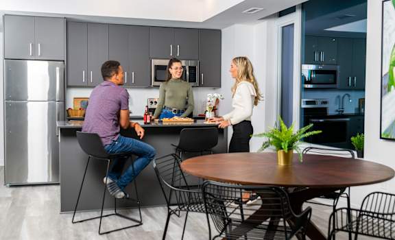 three people in a kitchen with a table