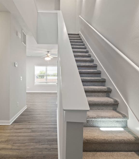 a view of a staircase in a home with white walls and grey carpeted stairsat Hillcrest Village, Springdale, AR 72762