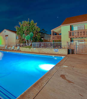 A swimming pool at night with lights reflecting on the water at Woodside Village