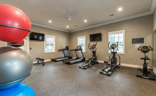 a gym with cardio machines and weights and a tv at Brighton Oaks, New Brighton, MN 55112