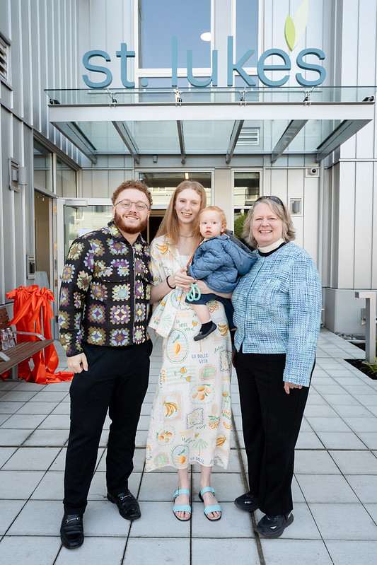 A family of four stands in front of a building with the name "St Luke's" on it.