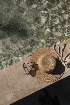 a straw hat and sunglasses sitting next to a pool