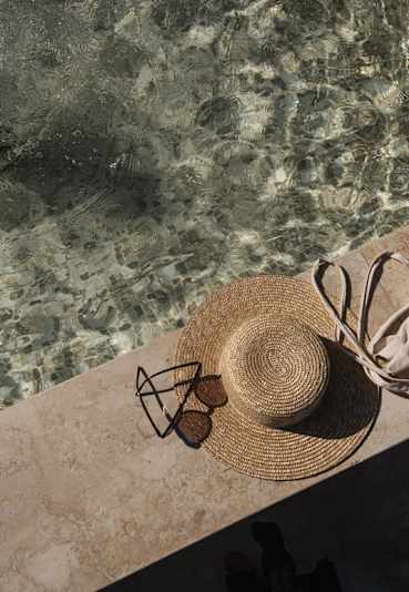 a straw hat and sunglasses sitting next to a pool