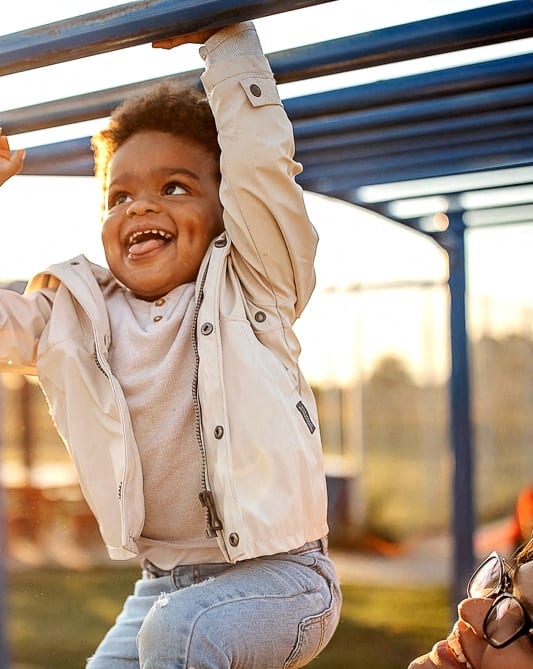 Lifestyle photo of a child and woman playing on a playset
