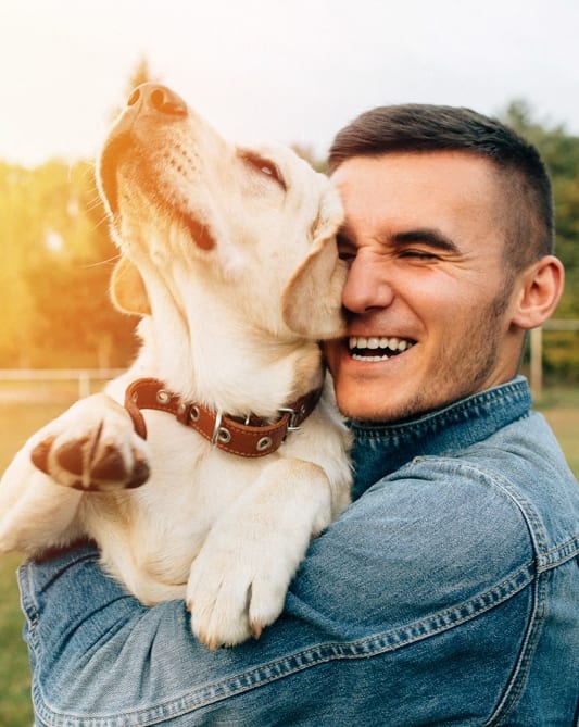 Lifestyle photo of a man smiling and holding his dog