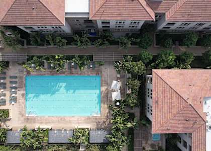 A swimming pool surrounded by trees and buildings.