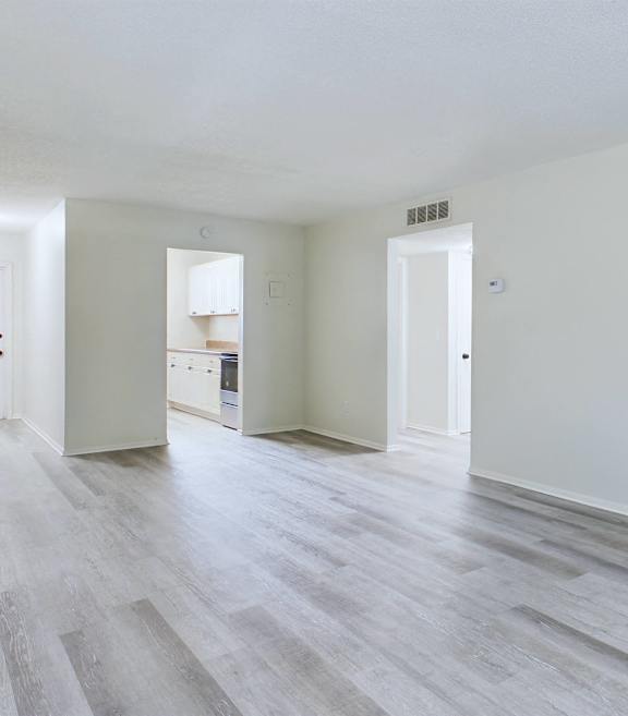 A spacious room with wooden flooring and white walls.