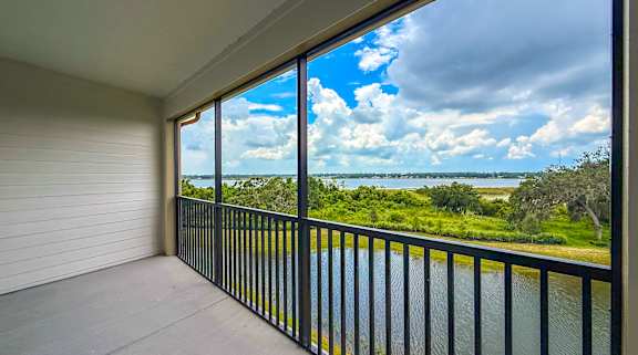 A balcony with a view of a body of water and greenery.