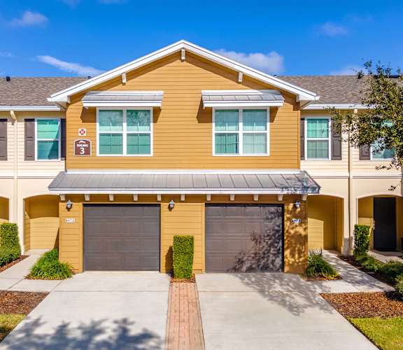 A yellow house with a garage door and a driveway.